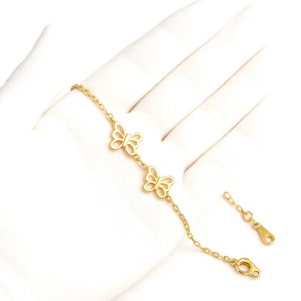 Close-up of the gold bracelet held by a white-gloved hand.