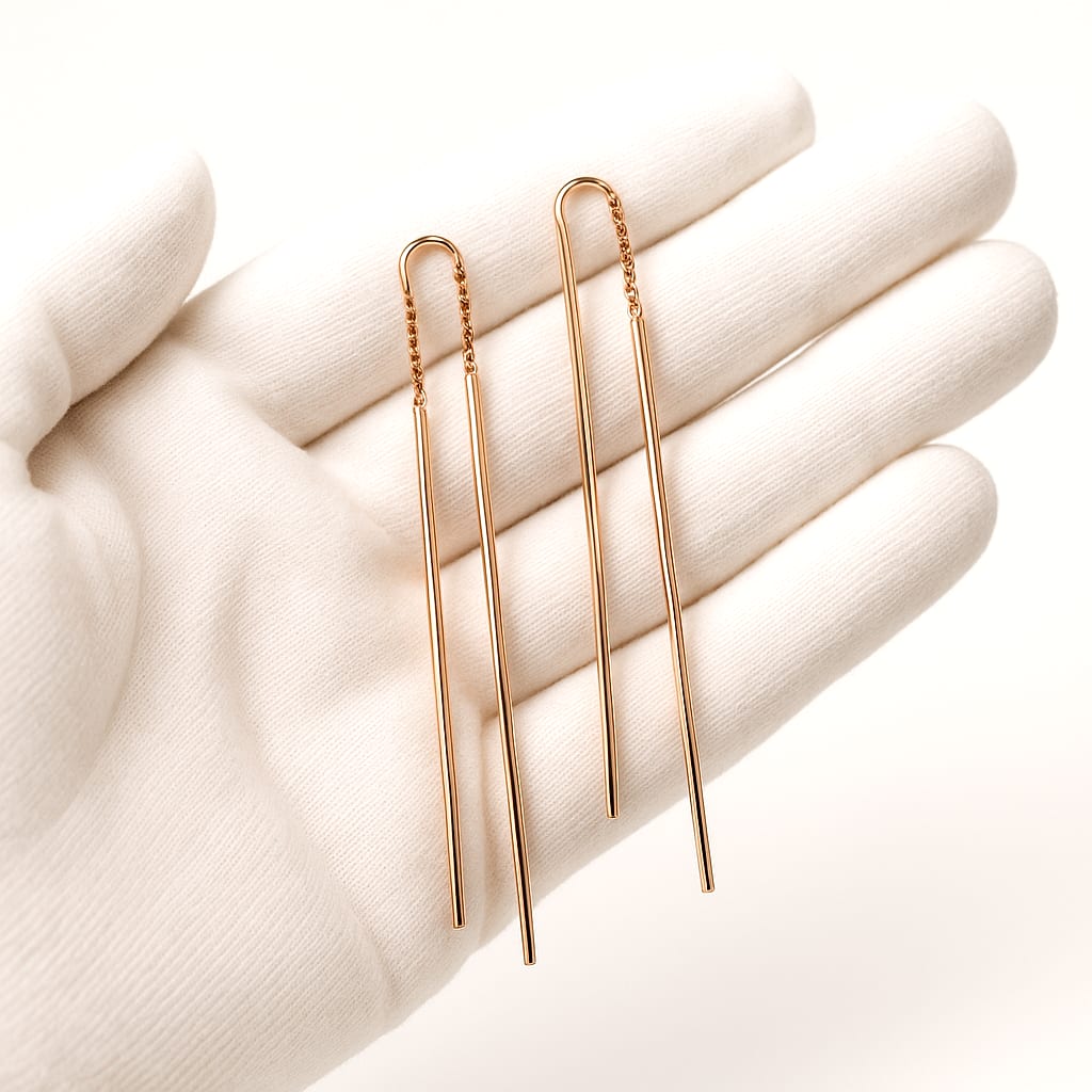 Close-up of 18K rose gold earrings held by a white-gloved hand