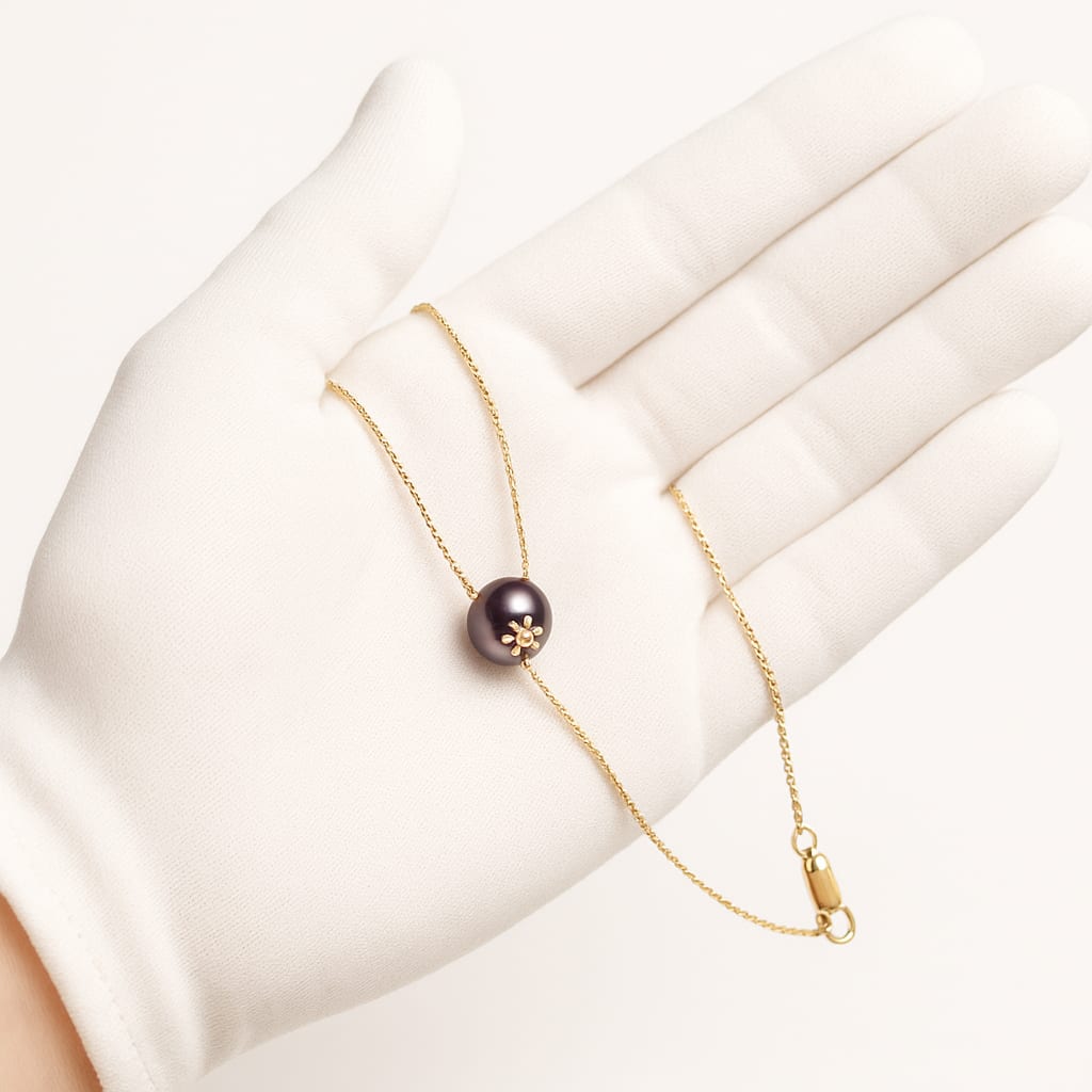 Detail of the 14K Gold Peacock Pearl Necklace held in a white glove